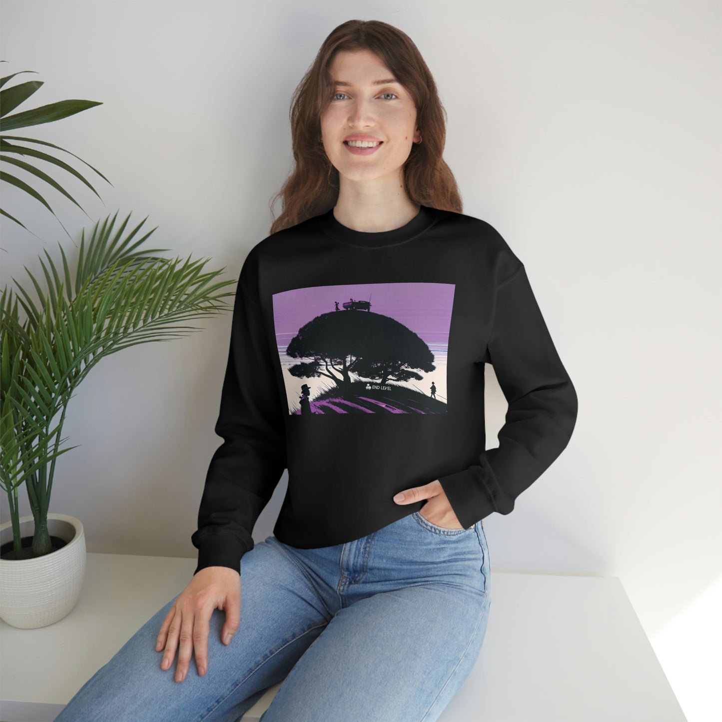 Woman with hand in jean pocket wearing black Tough Parking sweatshirt beside plant.