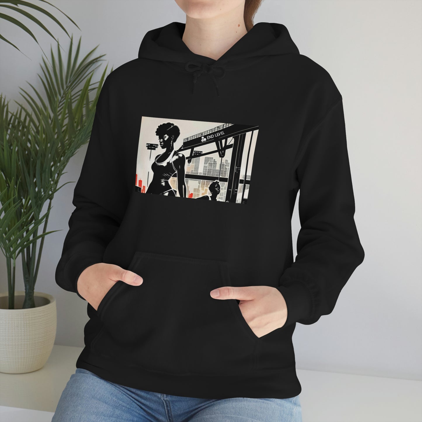 Woman wearing Life Ain't Easy design black hoodie beside a plant.