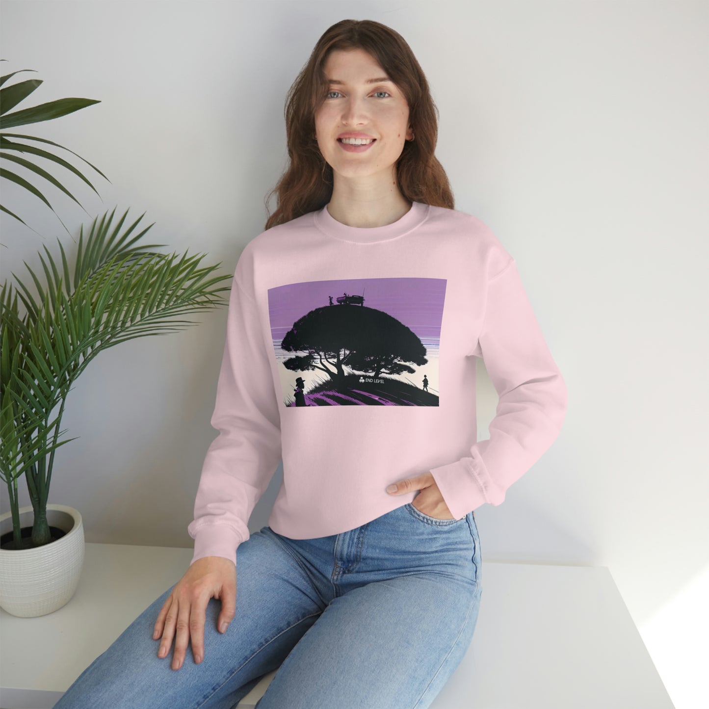 Woman with hand in jean pocket wearing pink Tough Parking sweatshirt beside plant.