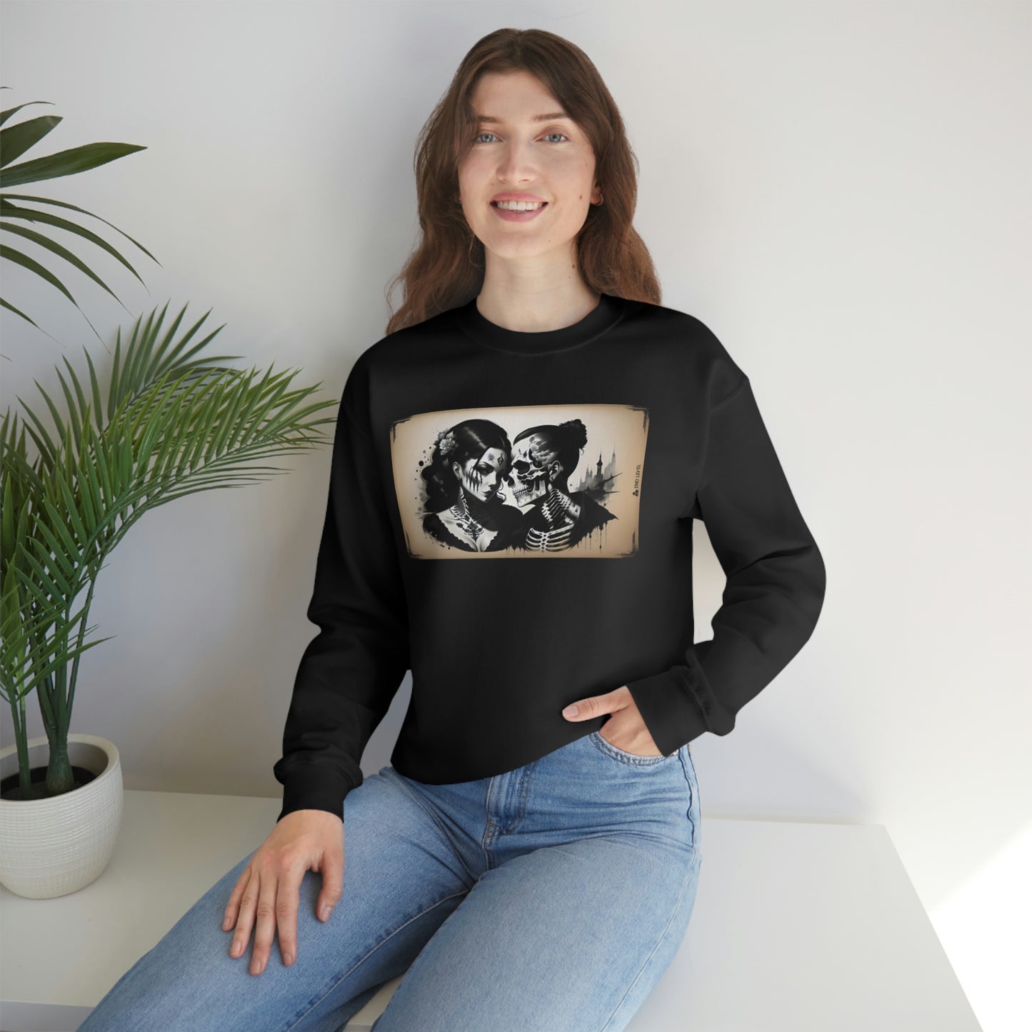 Woman with hand in jean pocket wearing Love Eternal black sweatshirt beside plant.